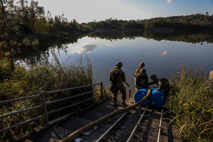 Marines with 2nd Platoon, Bulk Fuel Company, 9th Engineer Support Battalion, 3rd Marine Logistics Group, tie a suction hose to barrels on Jan. 28, 2019 at Central Training Area, Camp Hansen, Okinawa, Japan. Bulk fuel specialists assembled several fuel sites across the CTA to enhance their training and readiness within a harsh environment. The Marines set up and maintained their bulk fuel equipment during a week-long training evolution. (U.S. Marine Corps photo by Lance Cpl. Armando Elizalde)