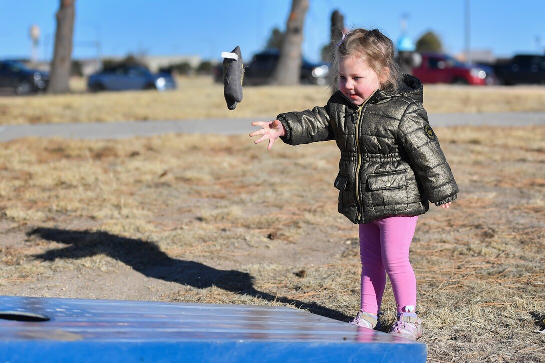 A child throws a sac towards a hole.