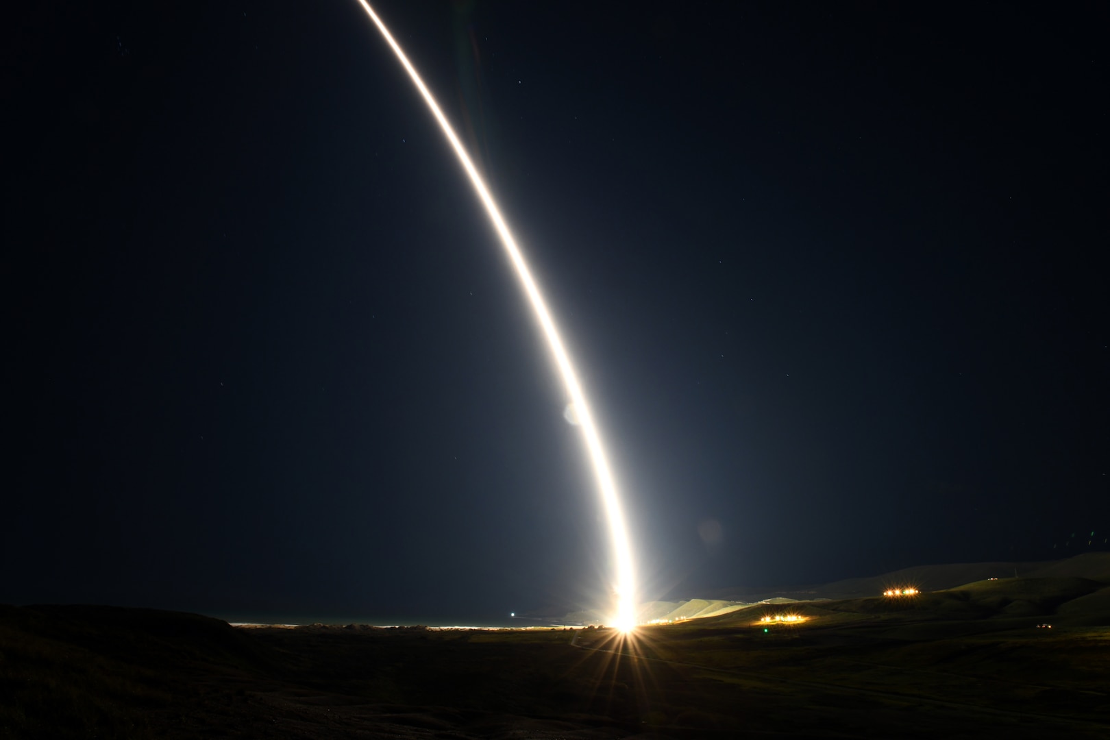A missile launches in  a dark sky.