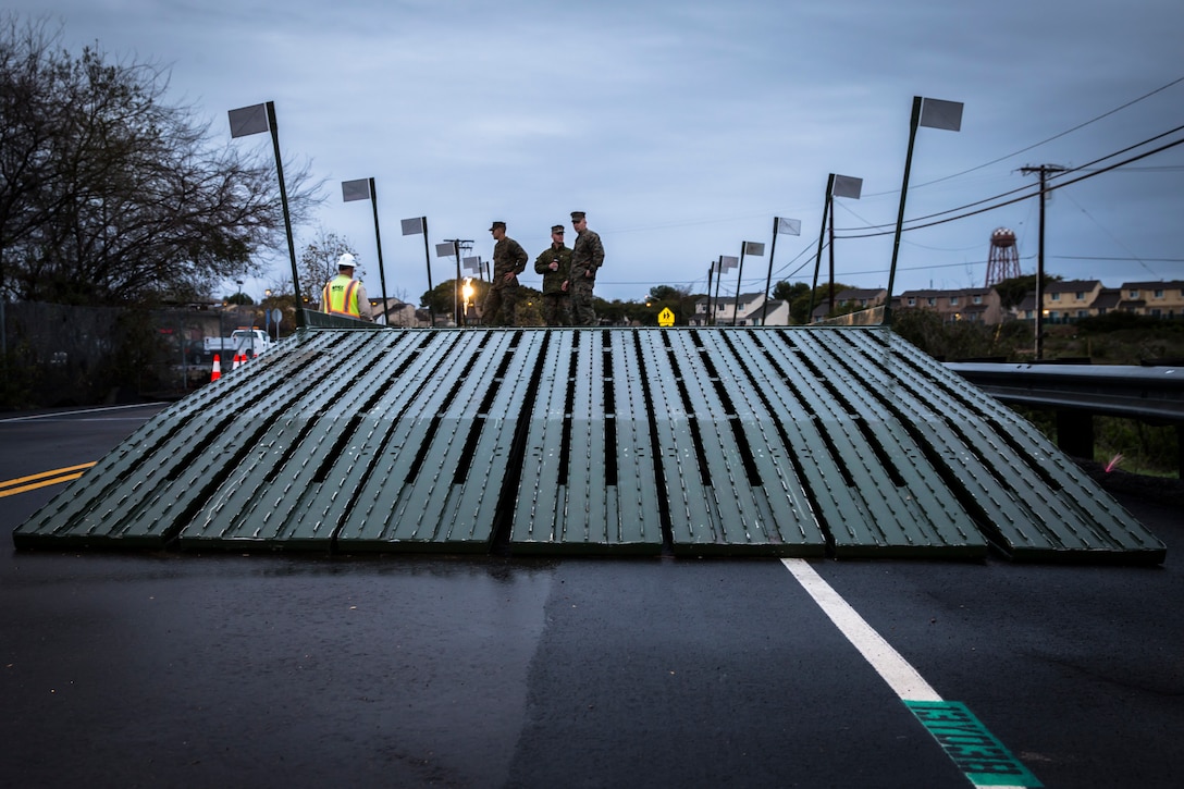 U.S. Marines with Bridge Company, 7th Engineer Support Battalion, 1st Marine Logistics Group and civilian contractors assess the safety and durability of a medium girder bridge on Carnes Road at Marine Corps Base Camp Pendleton, California, Feb. 5, 2019. The bridge was built to give emergency vehicles the ability to traverse a sinkhole that had developed in the road due to erosion. (U.S. Marine Corps photo by Cpl. Dylan Chagnon)