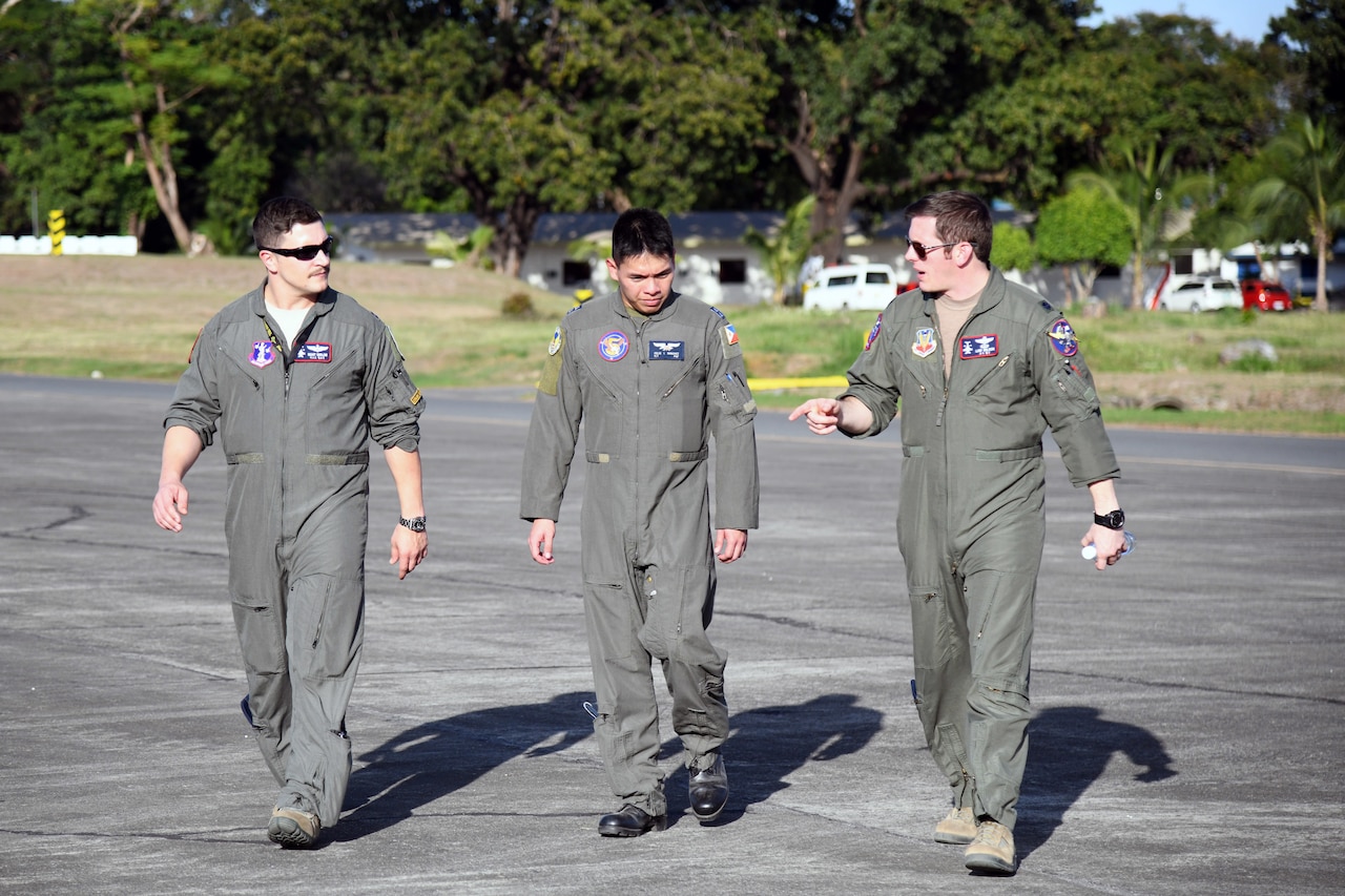 Three men walking side-by side down the flightline