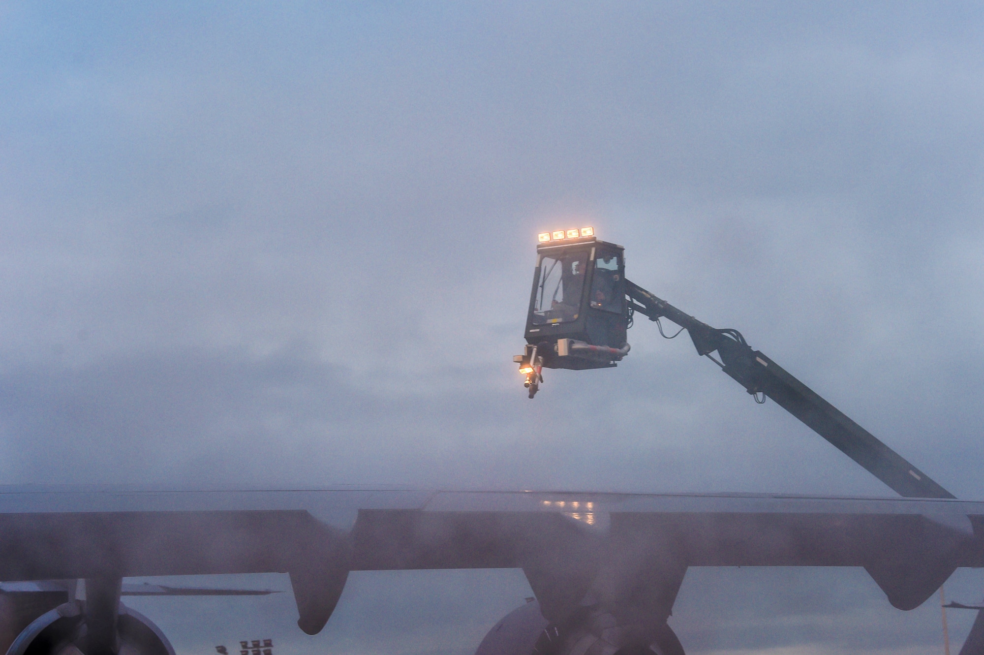 In the haze of a light fog, Tech. Sgt. Salomon Gutierrez, 62nd Aircraft Maintenance Squadron noncommissioned officer in charge of Silver Flight, prepares to spray deicing liquid onto the wing of a C-17 Globemaster III at Joint Base Lewis-McChord, Wash., Jan. 16, 2019. Snow and ice can make the aircraft heavy and freeze the flight control surfaces making it unsafe for take-off. (U.S. Air Force photo by Senior Airman Tryphena Mayhugh)