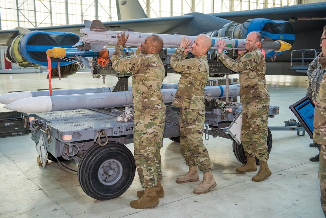Brig. Gen. E. John Teichert, 412th Test Wing commander (right), and Chief Master Sgt. Roosevelt Jones, 412th TW command chief, help 412th Maintenance Squadron first sergeant, Master Sgt. Robert Forbes, load an AIM-9X Sidewinder short-range air-to-air missile on an F-16 Fighting Falcon Feb. 6.  
This is a 188-pound missile that is normally loaded by hand with only good old fashioned Weapons load crew strength. 
The crew was given a weapons academic lesson by Staff Sgt. Michael Meyer, 412th Maintenance Group Weapons Standardization, where they were briefed on the Weapons Standardization mission as well as specific safety requirements for the loading operation.  
Afterwards, the crew loaded the munition under strict guidance and control by Staff Sgt. Robert Wagner, Airman 1st Class Cierra-Mae Hanson and Senior Airman Julio Zuleta. 
Although the chief and the general gave it their best, they didn’t quite meet all requirements for certification this time.  For now, actual Air Force Aircraft Armament Systems specialists will continue to load aircraft here at the Center of the Aerospace Testing Universe.