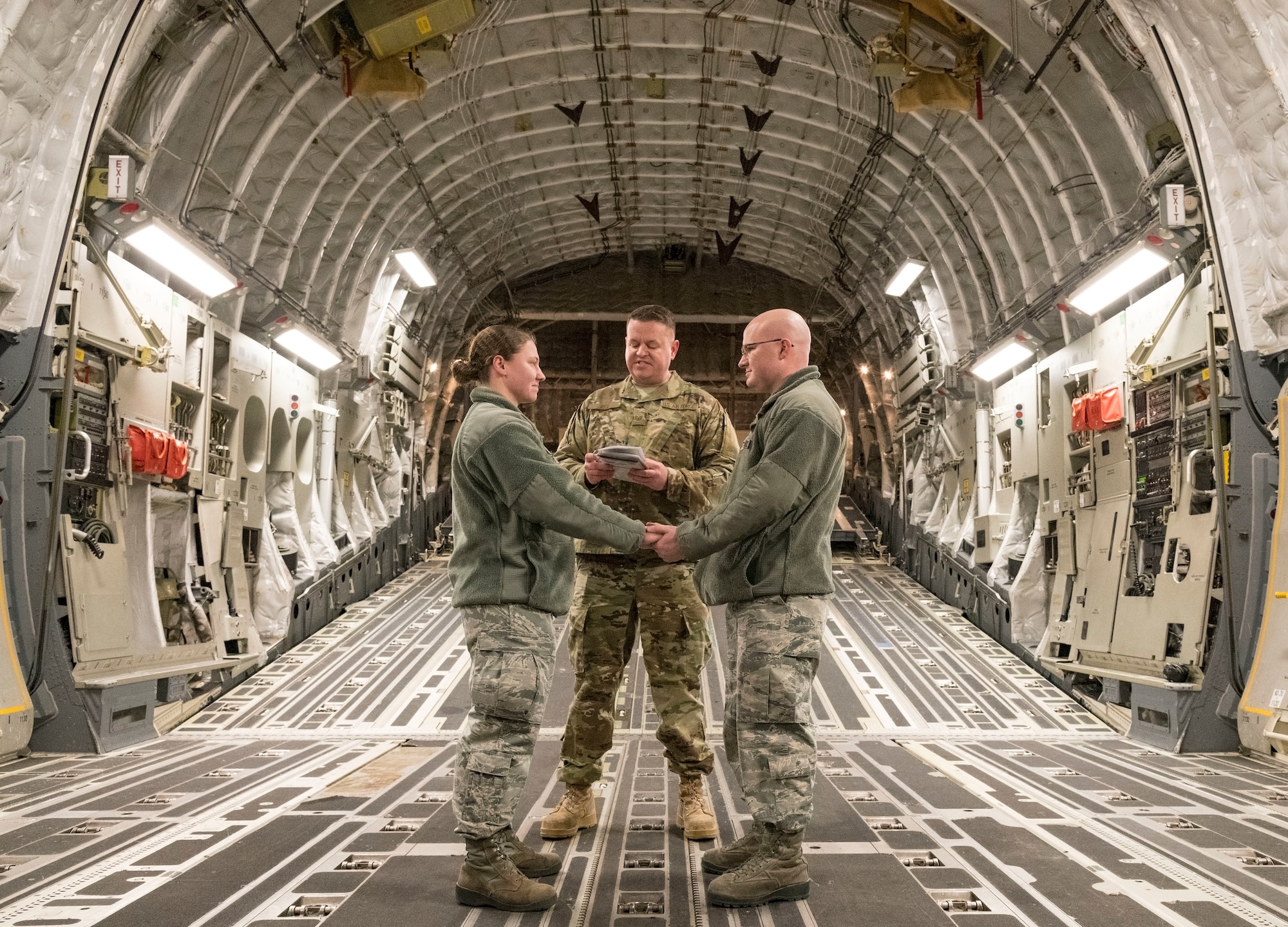 U.S. Air Force Tech. Sgt. Joseph Rice, 436th Aerial Port Squadron ramp operations supervisor, officiates a wedding ceremony for U.S. Airmen in the cargo compartment of a C-17 Globemaster III Jan. 29, 2018, at Dover Air Force Base, Delaware. Rice has been ordained for 10 years, but this was the first wedding he had ever officiated aboard an aircraft. (U.S. Air Force photo by Roland Balik)