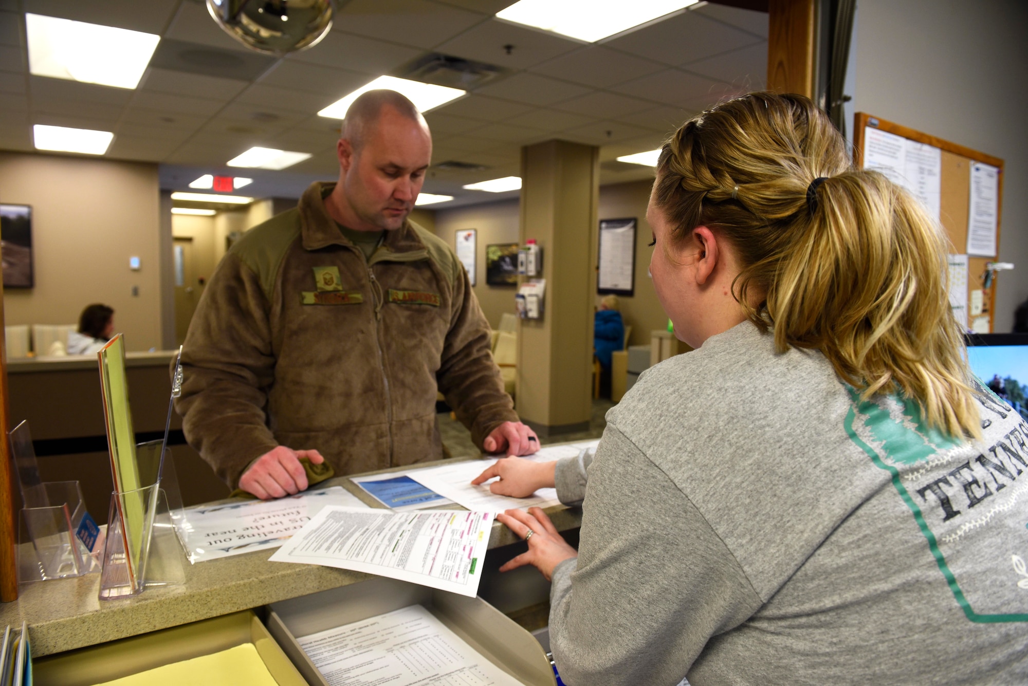 Taylor Kobylinski, 92nd Medical Operation Squadron medical administration assistant, assists an Airman with checking-in to the Family Health Center at Fairchild Air Force Base, Washington, Feb. 8, 2019. Data shows that initial fielding sites, like Fairchild, that document patient care in MHS Genesis continue to show increased operating capabilities in areas such as referrals processed, patients seen, prescriptions filled, and secure messaging. (U.S. Air Force photo/Airman 1st Class Lawrence Sena)