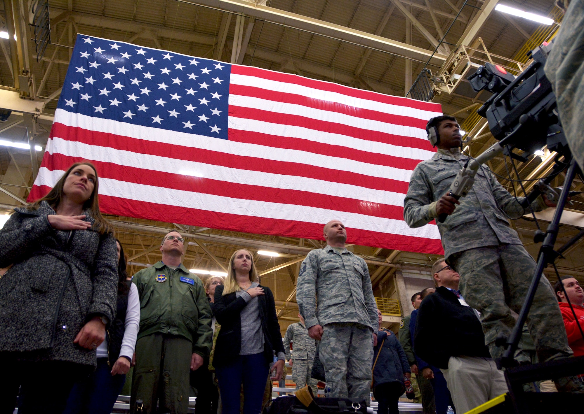 Guests of the KC-46A Pegasus arrival celebration stand during the national anthem at Altus Air Force Base, Oklahoma, Feb. 8, 2019. The KC‐46A provides improved capabilities over older Air Force air refueling aircraft to include boom and drogue refueling on the same sortie, a refueling capability of more than 212,000 pounds of fuel and palletized cargo up to 65,000 pounds, depending on fuel storage configuration. (U.S. Air Force photo by Tech. Sgt. Samantha Mathison)