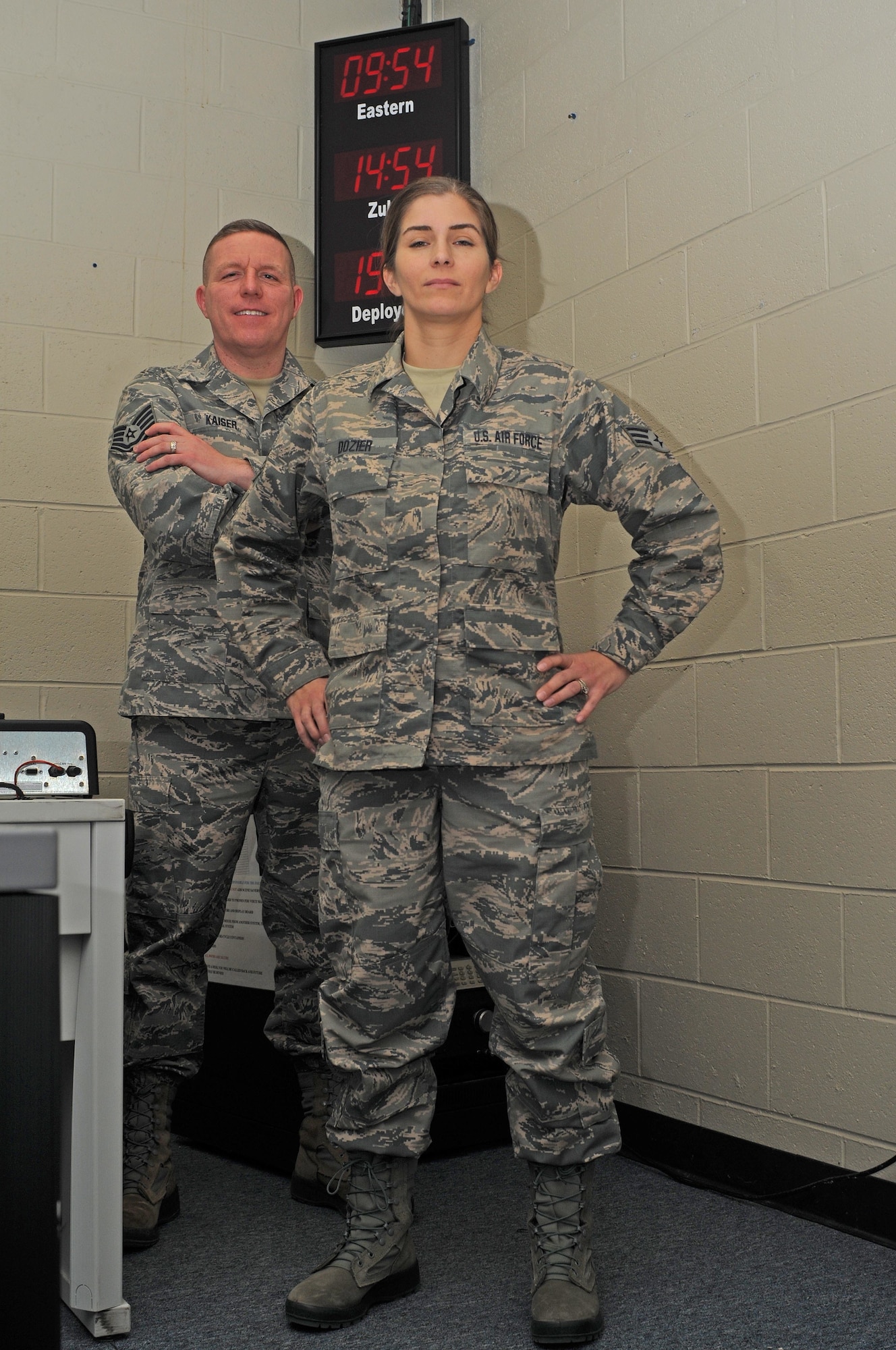 Two military members stand in a room with a clock