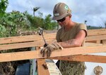 TINIAN, Northern Mariana Islands --- Builder 3rd Class Matthew Winnett, assigned to Naval Mobile Construction Battalion 3, Det. Tinian, nails in a truss, Jan. 25, for a temporary emergency roof for a home that was damaged during Super Typhoon Yutu.