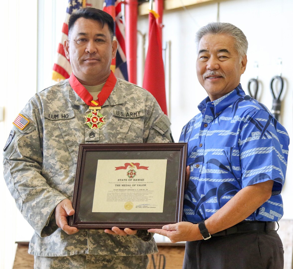 Gov. David Ige presents State Medal of Valor recipient, Staff Sgt. Gregory A.Y. Lum Ho, Jr., with award certificate during  a ceremony held on Feb. 9, 2019, at Wheeler Army Airfield, Hawaii. Lum Ho was awarded the State Medal of Valor for ignoring substantial risk to his own life to ensure the rescue of a family of six while supporting Hawaii National Guard response efforts to Tropical Storm Lane on Aug. 23, 2018,