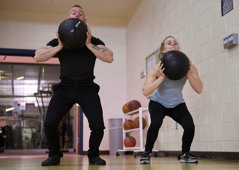 U.S. Air Force Senior Airman Tyler, 30th Intelligence Squadron, and Elise Lang, daughter of retired U.S. Air Force Lt. Col. Kenneth Lang, throw medicine balls at Joint Base Langley-Eustis, Virginia, Feb. 7, 2019.