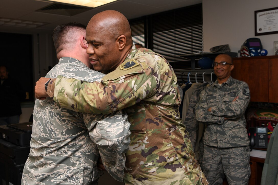 Chief Master Sgt. Anthony Potts (right), Oklahoma Air National Guard state command chief, Oklahoma Joint Force Headquarters, Oklahoma City, hugs Master Sgt. Scott Crim (left), a 137th Special Operations Logistics Readiness Squadron (137th SOLRS) heavy equipment mechanic, during an informal coining in Crim's office at Will Rogers Air National Guard Base in Oklahoma City, Feb. 5, 2019. Crim and his wingman, Tech. Sgt. Jacob Hanchett, also a 137th SOLRS heavy equipment mechanic, were coined after reviving a baby at a nearby pizza restaurant during their lunch break. (U.S. Air National Guard Photo by Tech. Sgt. Kasey M. Phipps)