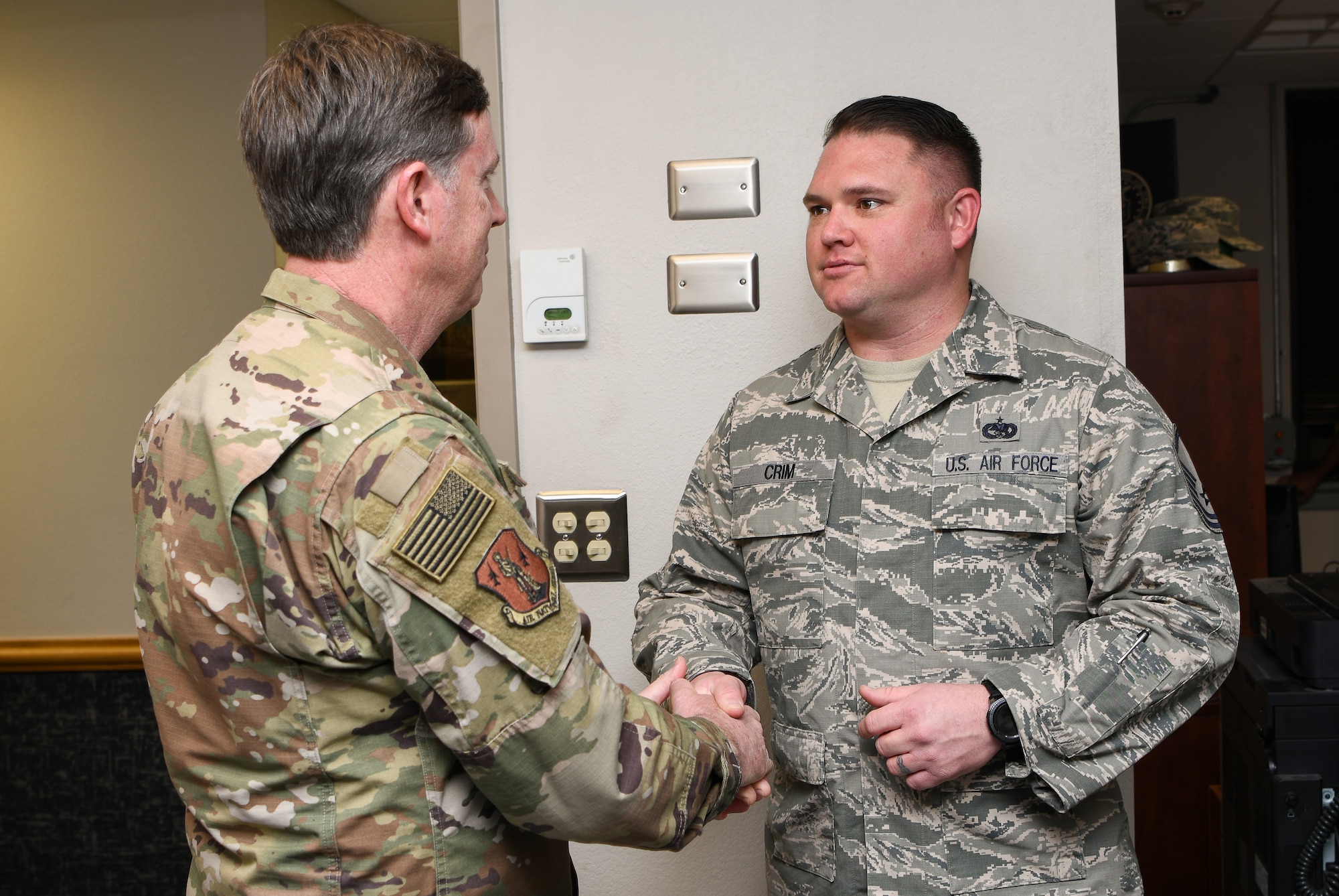 Brig. Gen. Thomas Ryan (left), Oklahoma National Guard assistant adjutant general – air, Oklahoma Joint Force Headquarters, Oklahoma City, shakes the hand of Master Sgt. Scott Crim (right), a 137th Special Operations Logistics Readiness Squadron (137th SOLRS) heavy equipment mechanic, during an informal coining in Crim's office at Will Rogers Air National Guard Base in Oklahoma City, Feb. 5, 2019. Crim and his wingman, Tech. Sgt. Jacob Hanchett, also a 137th SOLRS heavy equipment mechanic, were coined after reviving a baby at a nearby pizza restaurant during their lunch break. (U.S. Air National Guard Photo by Tech. Sgt. Kasey M. Phipps)