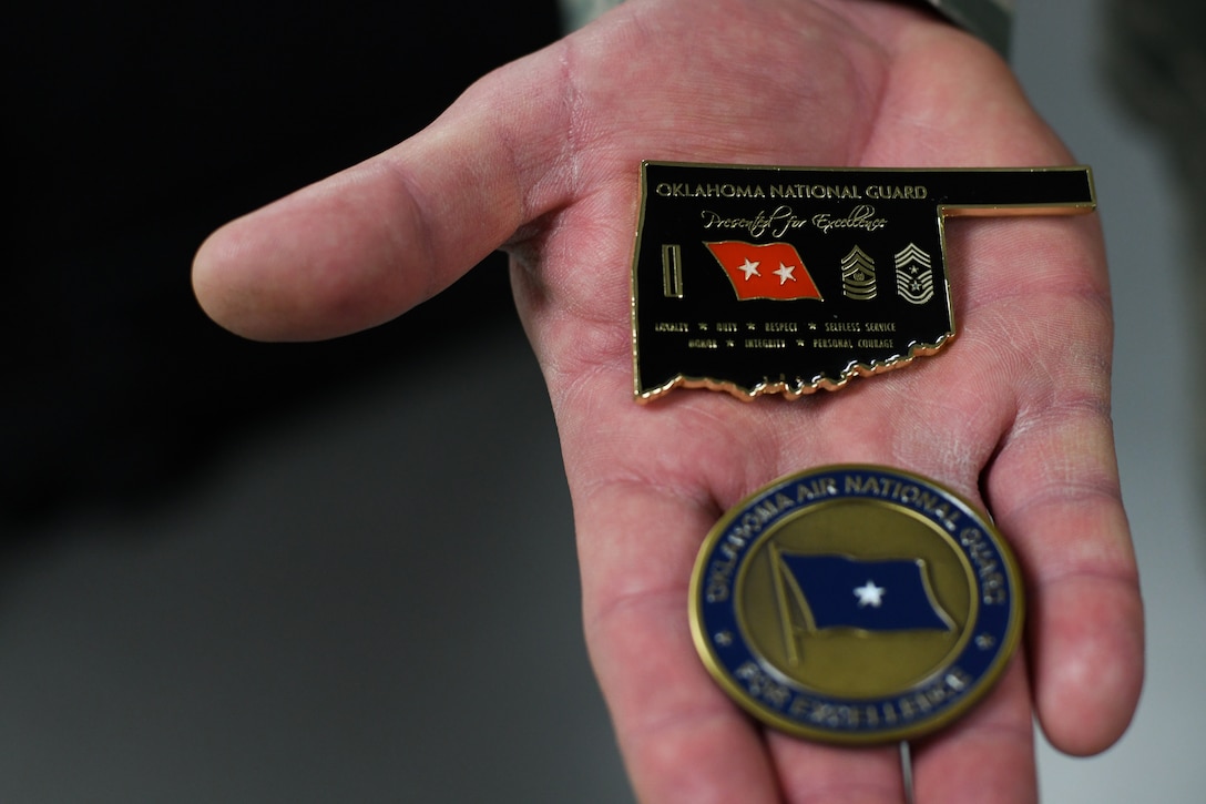 Master Sgt. Scott Crim, a 137th Special Operations Logistics Readiness Squadron (137th SOLRS) heavy equipment mechanic, holds two coins – one from the Oklahoma Air National Guard state command chief (top) and one from the Oklahoma National Guard assistant adjutant general – air (bottom) – after an informal coining in Crim's office at Will Rogers Air National Guard Base in Oklahoma City, Feb. 5, 2019. Crim and his wingman, Tech. Sgt. Jacob Hanchett, also a 137th SOLRS heavy equipment mechanic, were coined after reviving a baby at a nearby pizza restaurant during their lunch break. (U.S. Air National Guard Photo by Tech. Sgt. Kasey M. Phipps)