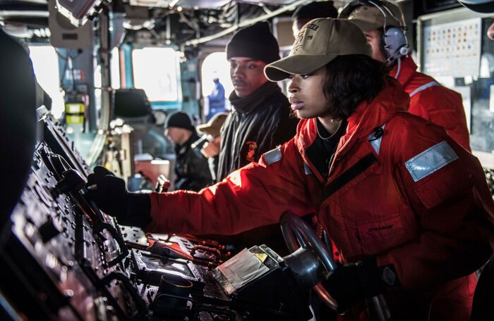 Boatswain's Mate Seaman Edajah Lawless-Gregory mans the helm aboard the Arleigh Burke-class guided-missile destroyer USS Porter (DDG 78) while departing Copenhagen, Denmark, Feb. 4, 2019.