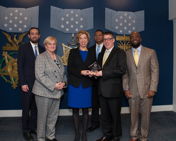 Eleanor M. Lord, center, undersecretary of defense for acquisition and sustainment, presents a Department of Defense Acquisition Workforce Development Innovation Award to (from left) SSC Atlantic Executive Director Christopher Miller, Total Workforce lead Pamela K. Bell, team lead Fred Bisel and team members Kamau Buffalo and Wesley Jones. The team received the award for their work on creating the Cyber Education and Certification Readiness Facility based in Charleston, S.C.