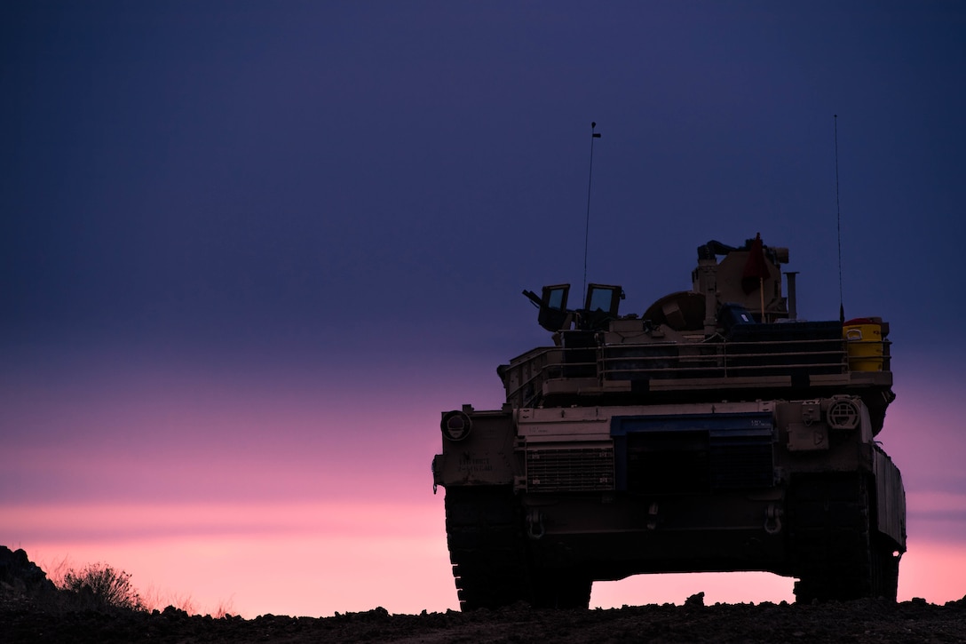 A tank parked at sunset.