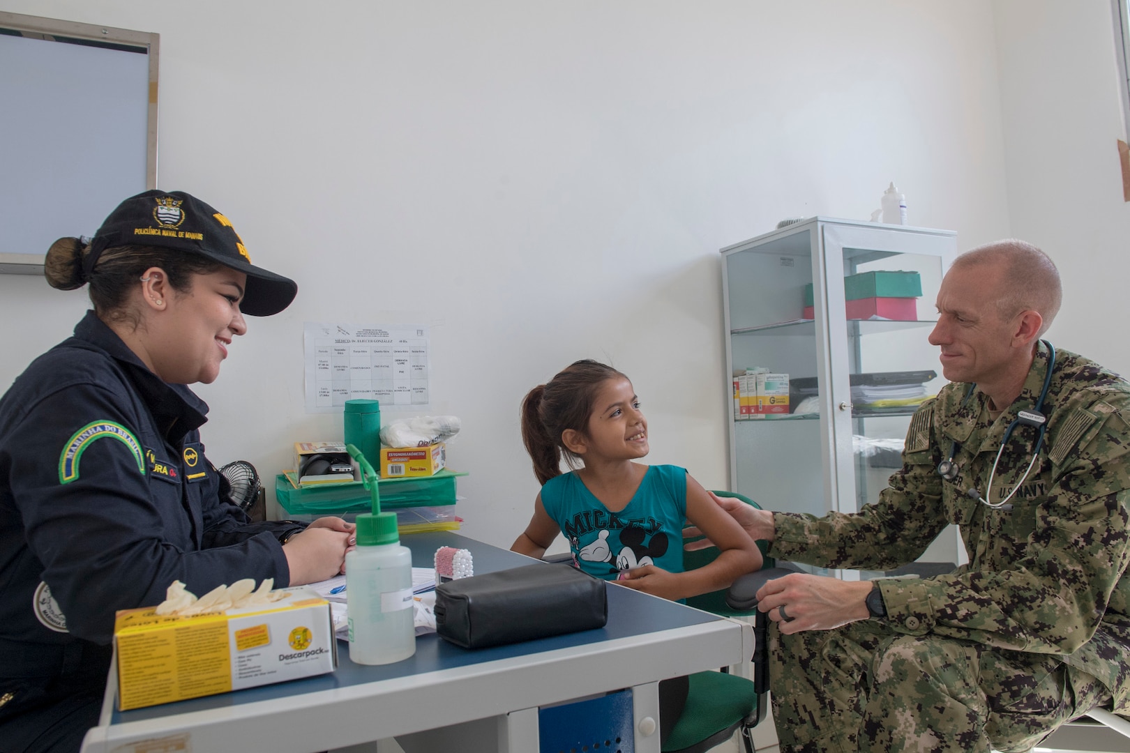 Brazilian Navy 1st Lt. Livia Laura, left, and Cmdr. Edmund Milder, right, examine a young patient during a visit to the Heraclio Emiliano Moda medical clinic in Axinim, Brazil, Feb. 6.