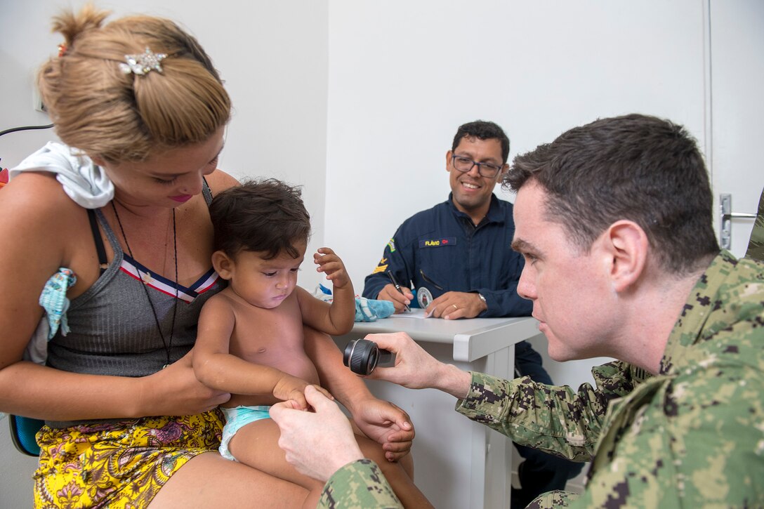 Lt. Cmdr. John Roman examines a young patient during a visit to the Heraclio Emiliano Moda medical clinic in Axinim, Brazil, Feb. 6.