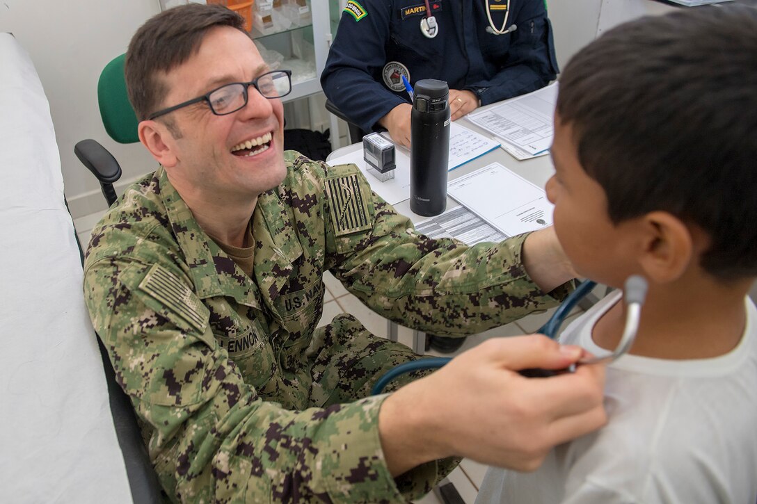 Lt. Cmdr. Robert Lennon laughs as a young patient uses his stethoscope during a visit to the Heraclio Emiliano Moda medical clinic in Axinim, Brazil, Feb. 6