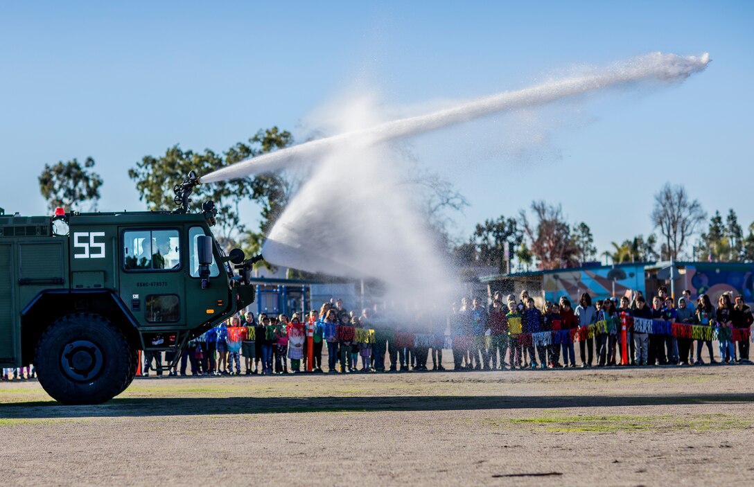 Marine Corps Air Station Miramar Aircraft Rescue and Firefighting (ARFF) Marines demonstrate the capabilities of the fire hose on a P-19R during an ARFF demonstration at the Curie Elementary School, University City, Calif., Feb. 8. The Marines conducted this demonstration to teach students about the Aircraft Rescue and Firefighting military occupational specialty as well as foster cohesion with the surrounding community. (U.S. Marine Corps photo by Sgt. Jake McClung)