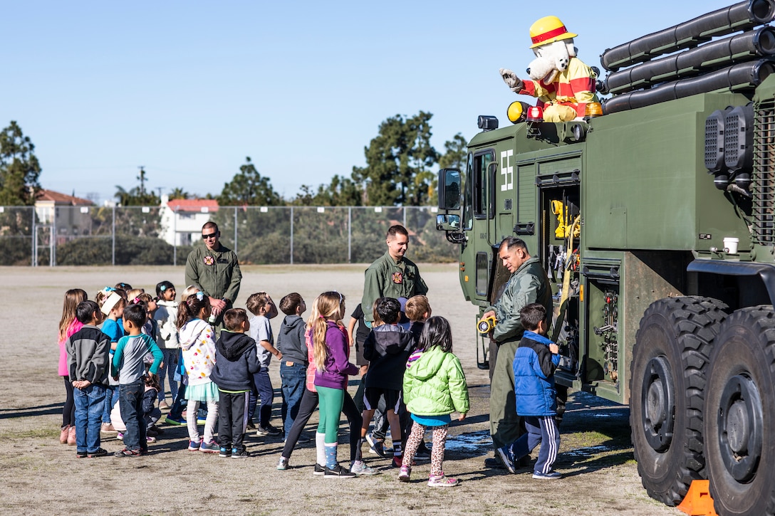 Curie Elementary School students interact with Sparky, the Marine Corps Air Station Miramar Aircraft Rescue and Firefighting (ARFF) mascot, during an ARFF demonstration at the Curie Elementary School, University City, Calif., Feb. 8. The Marines conducted this demonstration to teach students about the Aircraft Rescue and Firefighting military occupational specialty as well as foster cohesion with the surrounding community. (U.S. Marine Corps photo by Sgt. Jake McClung)