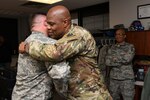 Chief Master Sgt. Anthony Potts, right, Oklahoma Air National Guard state command chief, Oklahoma Joint Force Headquarters, hugs Master Sgt. Scott Crim, a 137th Special Operations Logistics Readiness Squadron (137th SOLRS) heavy equipment mechanic, during an informal coining in Crim's office at Will Rogers Air National Guard Base in Oklahoma City, Feb. 5, 2019.
