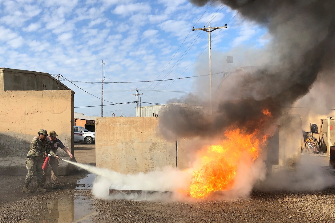 A service member puts out a fire with a fire extinguisher.