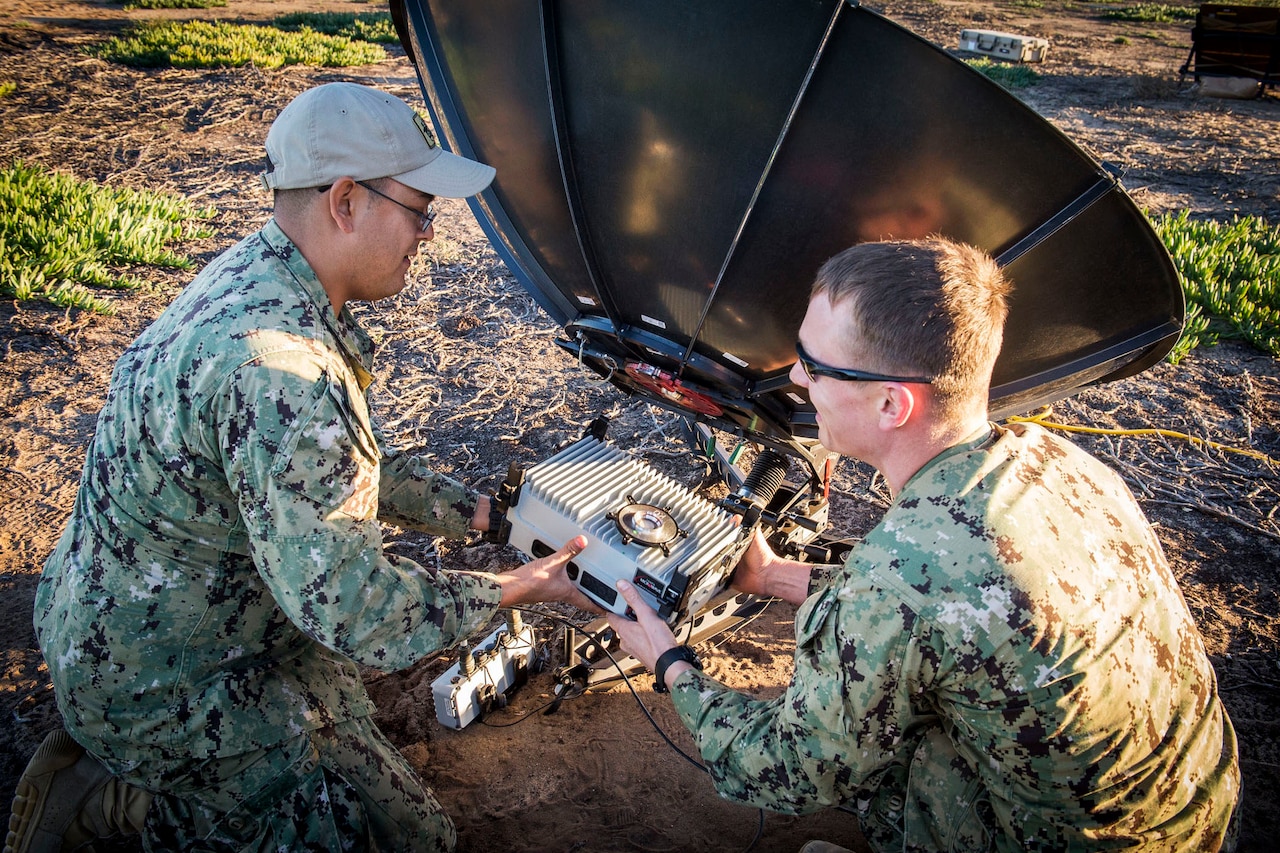 Sailors in camouflage uniforms assemble satellite communication unit