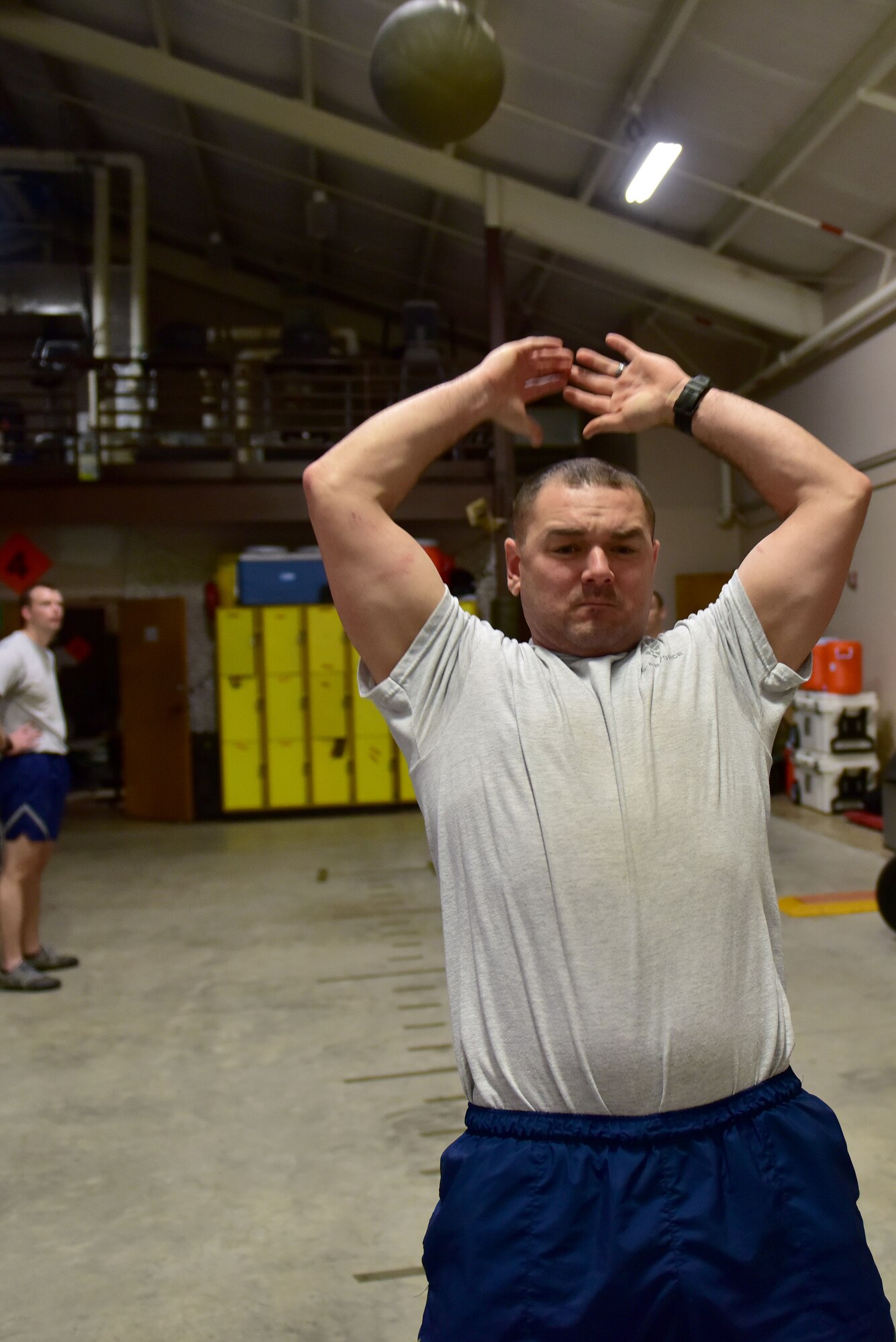 A man wearing the Air Force physical training gear throws a medicine ball.