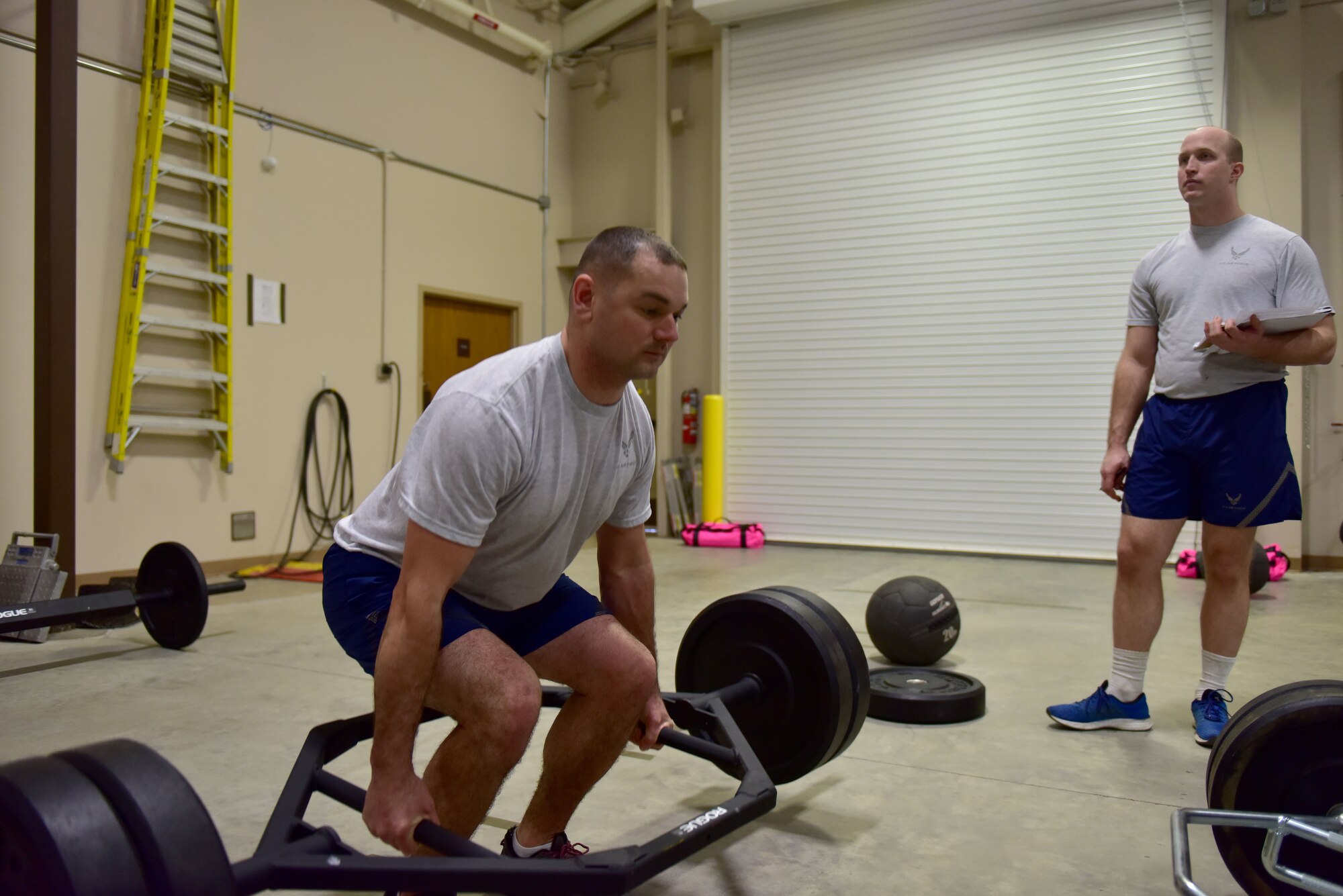 A man wearing the Air Force phyisical training gear does a deadlift.