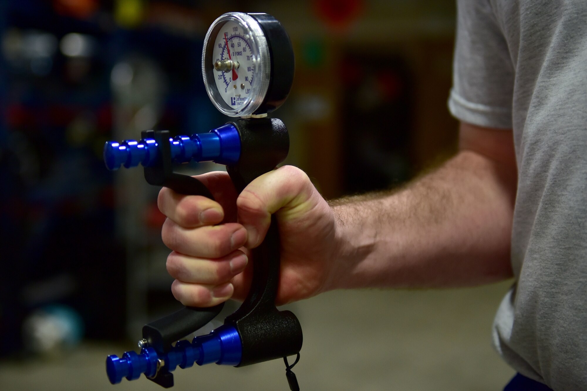 A hand squeezes a device that measures how strong someone's grip strength is.