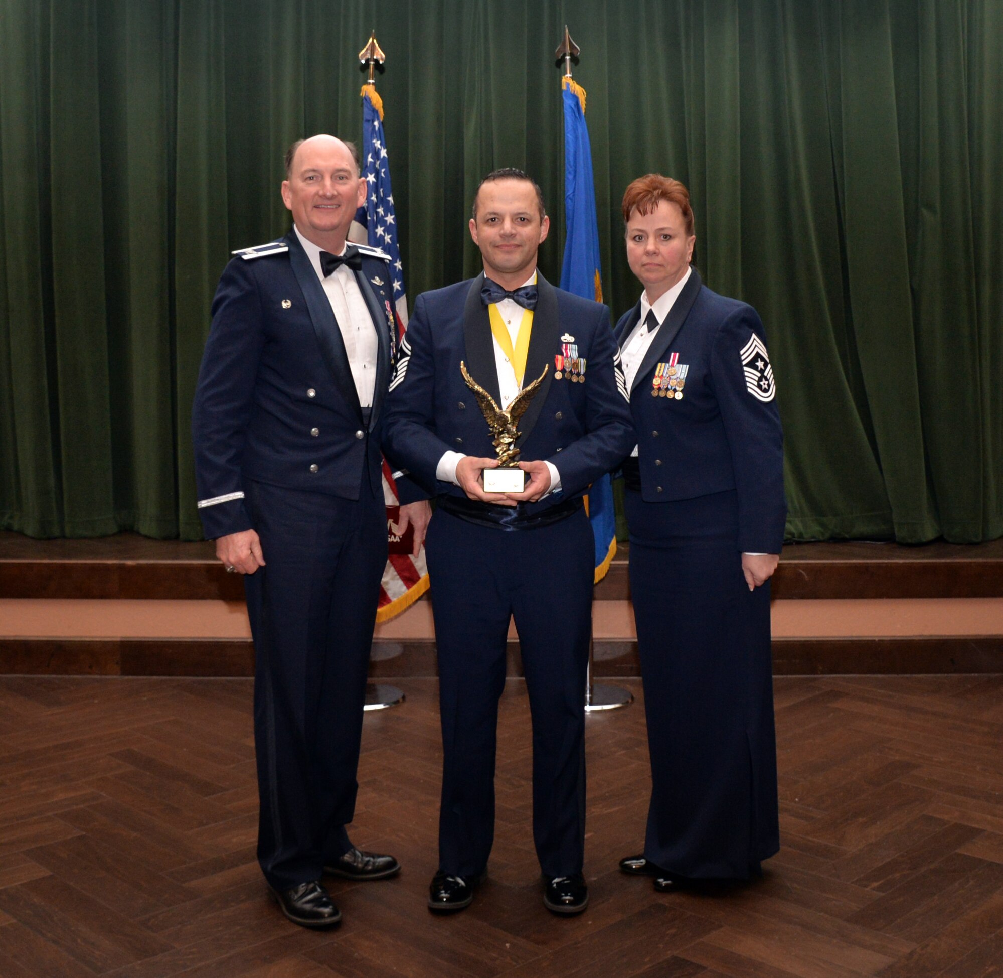 Col. Thomas K. Smith, 433rd Airlift Wing commander, and 433rd AW Command Chief Master Sgt. Shana C. Cullum, award Senior Master Sgt. Arturo Loya, 74th Aerial Port Squadron, as the First Sergeant of the Year at the 433rd AW annual awards banquet at Joint Base San Antonio-Lackland, Texas Feb. 9, 2019.