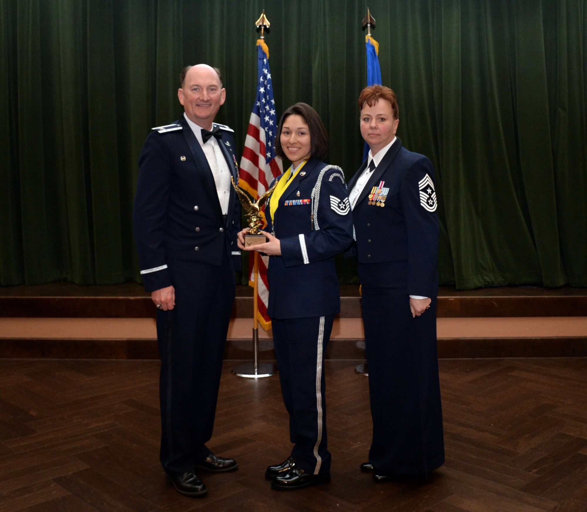Col. Thomas K. Smith, 433rd Airlift Wing commander, and 433rd AW Command Chief Master Sgt. Shana C. Cullum, award Tech. Sgt. Stephanie Escobedo, 433rd Aerospace Medicine Squadron, as the Honor Guard Member of the Year at the 433rd AW annual awards banquet at Joint Base San Antonio-Lackland, Texas Feb. 9, 2019.
