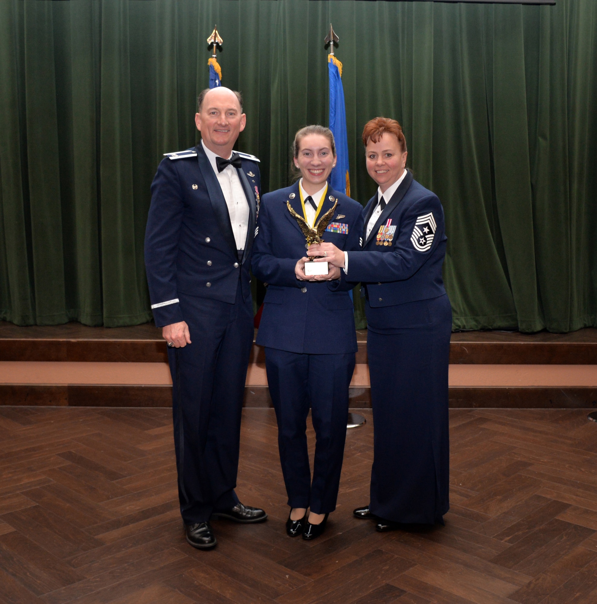 Col. Thomas K. Smith, 433rd Airlift Wing commander, and 433rd AW Command Chief Master Sgt. Shana C. Cullum, award Senior Airman Kryssianna Paula, 68th Airlift Squadron, as the Airman of the Year at the 433rd AW annual awards banquet at Joint Base San Antonio-Lackland, Texas Feb. 9, 2019.
