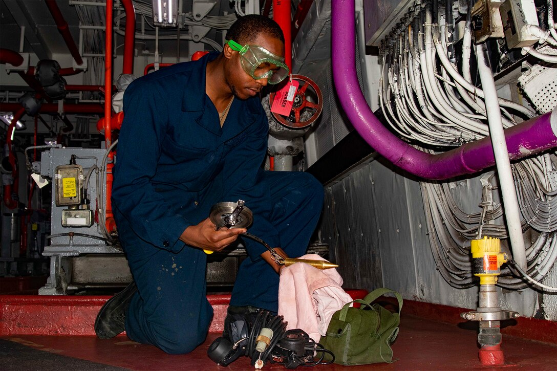 A service member performs maintenance on a ship.