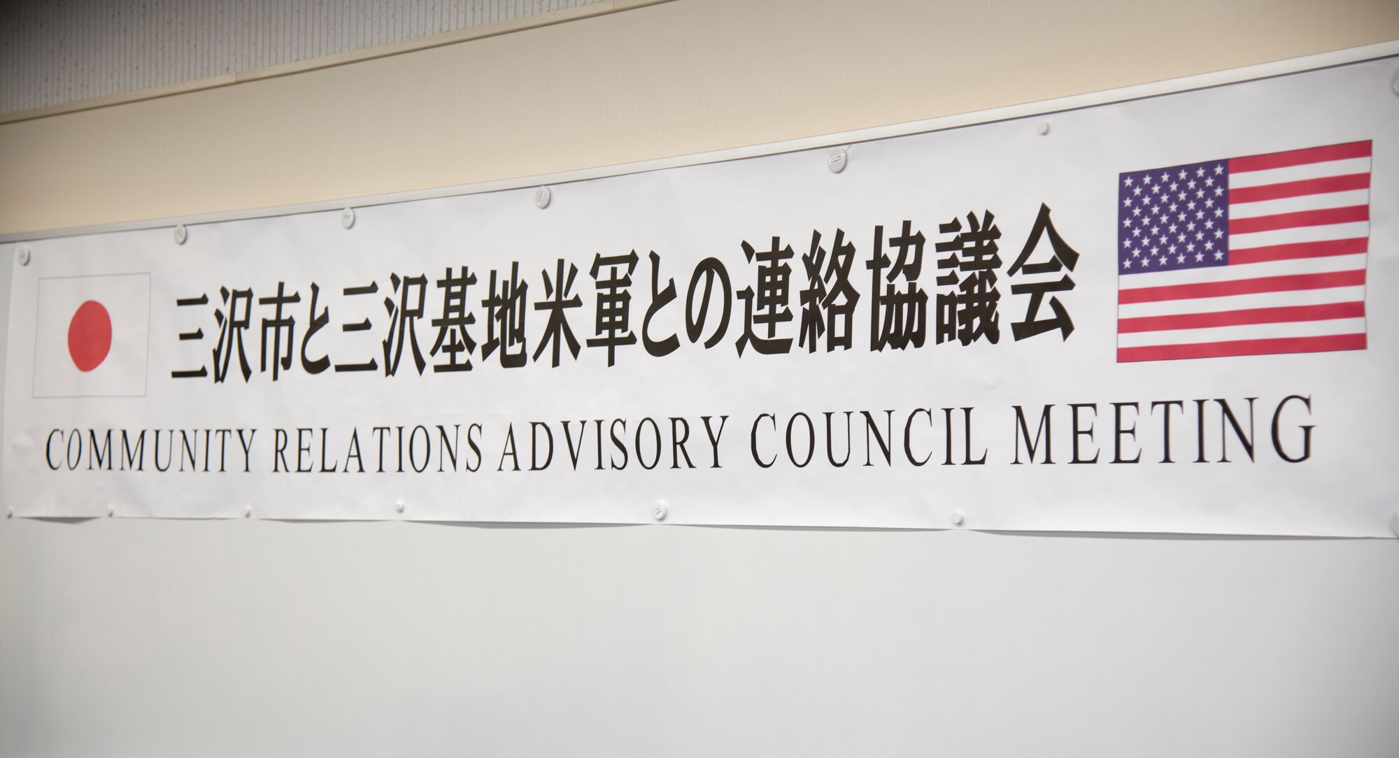 An official banner lines the back wall of the Community Relations Advisory Council meeting at the Misawa International Center, Japan, Feb. 5, 2019. The banner bears the flags of both the U.S. and Japan, indicating the strong unity of purpose among the two nations. (U.S. Air Force photo by Branden Yamada)
