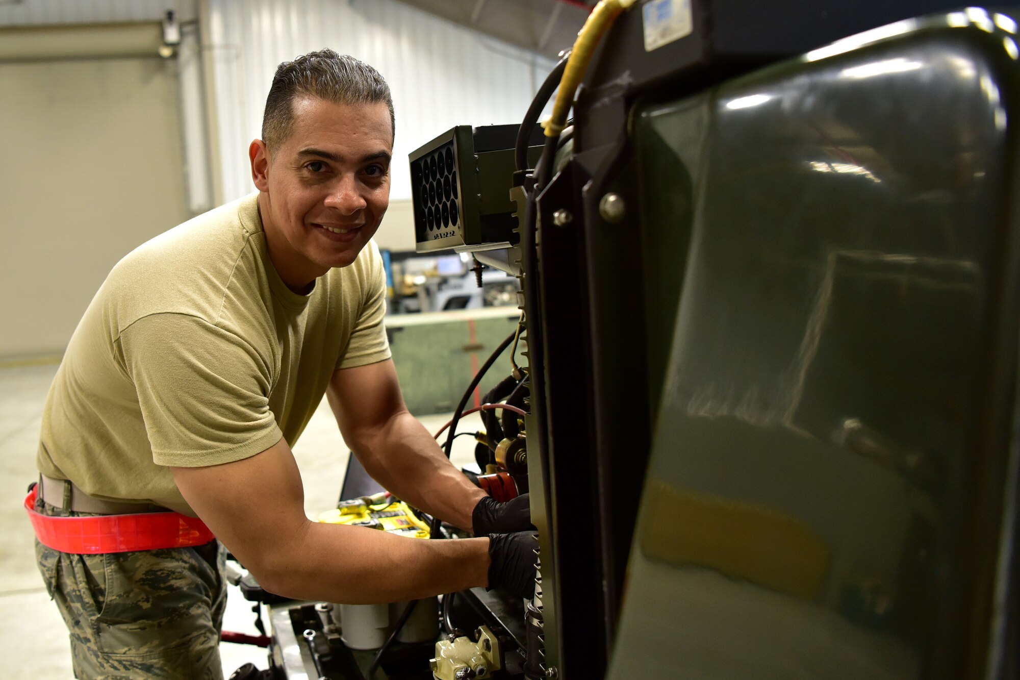 Airman poses for a photo next to a machine.