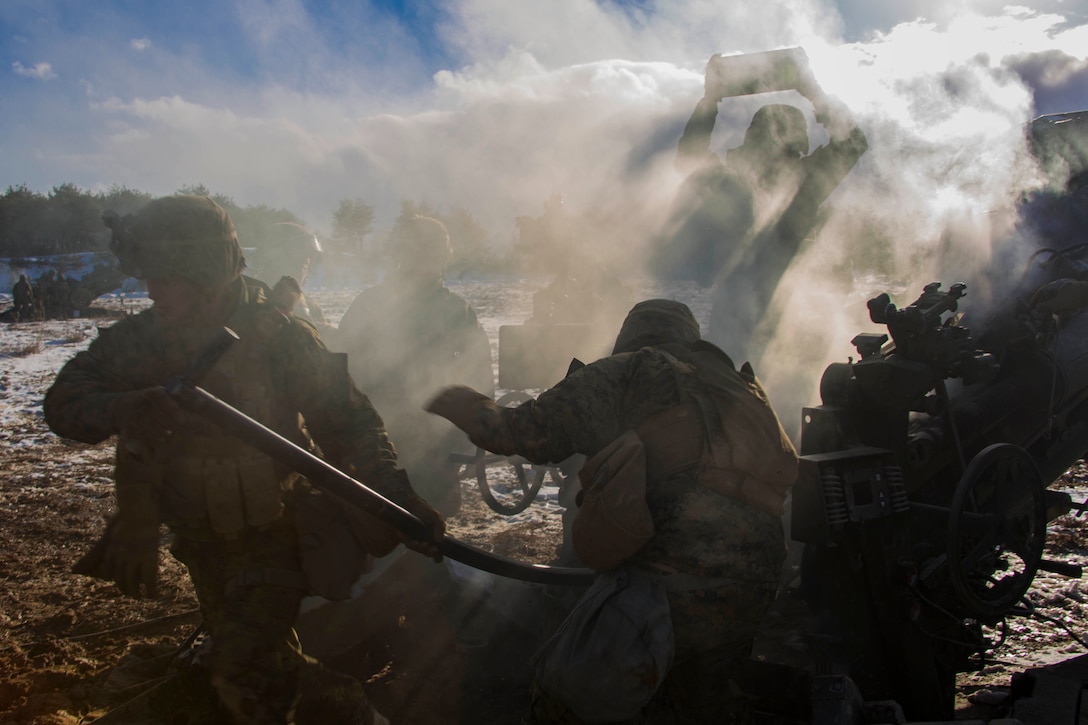 Marines load shells into a howitzer.