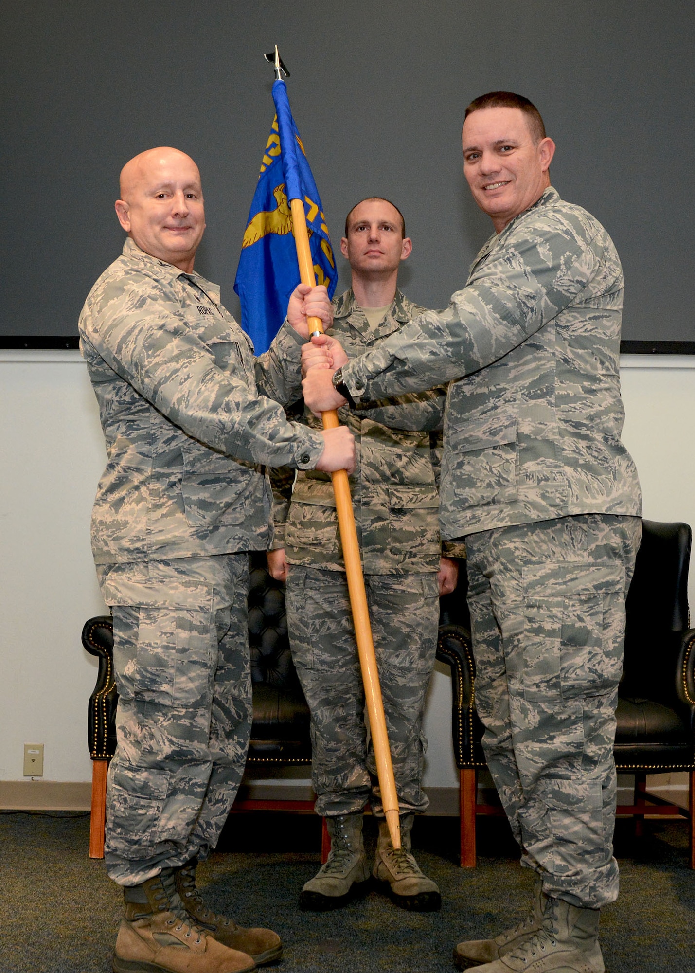 Lt. Col. William Young, right, relinquishes command of the 72nd Aerial Port Squadron Feb. 10, 2019, at Tinker Air Force Base, Oklahoma to Col. Richard Ropac, 507th Mission Support Group commander, who passed the guidon to Col. Darryl McLean moments later. (U.S. Air Force photo by Tech. Sgt. Samantha Mathison)