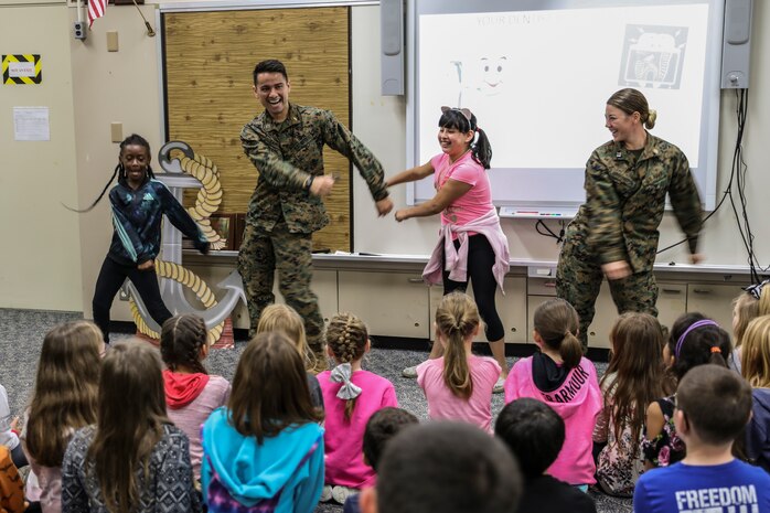 Navy Lt. Kristopher Zamora, center left, and Lt. Kathryn Harrington, right, do the “floss” dance with students from Kinser Elementary School Feb. 5, 2019 on Camp Kinser, Okinawa, Japan. Sailors from Naval clinics in Okinawa held a presentation to promote oral health awareness during National Children’s Dental Health Month. Zamora, a general dentist with Branch Dental Clinic Hansen, 3rd Dental Bn., 3rd Marine Logistics Group, is a native of Caldwell, Idaho. Harrington, a general dentist with Branch Dental Clinic Futenma, 3rd Dental Bn., 3rd MLG, is a native of Cleveland, Ohio. (U.S. Marine Corps photo by Armando Elizalde)