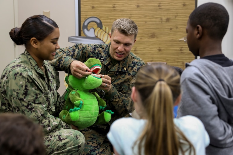 Navy Lt. Michael J. Lawrence, center left, and Seaman Lauryn A. Dunning, left, demonstrate how to properly floss teeth to students from Kinser Elementary School Feb. 5, 2019 on Camp Kinser, Okinawa, Japan. Sailors from Naval clinics in Okinawa held a presentation to promote oral health awareness during National Children’s Dental Health Month. Lawrence, a general dentist with Branch Dental Clinic Evans, 3rd Dental Battalion, 3rd Marine Logistics Group, is a native of Troutdale, Oregon. Dunning, a hospital corpsman with Branch Dental Clinic Futenma, 3rd Dental Bn., 3rd MLG, is native of New Orleans, Louisiana. (U.S. Marine Corps photo by Lance Cpl. Armando Elizalde)