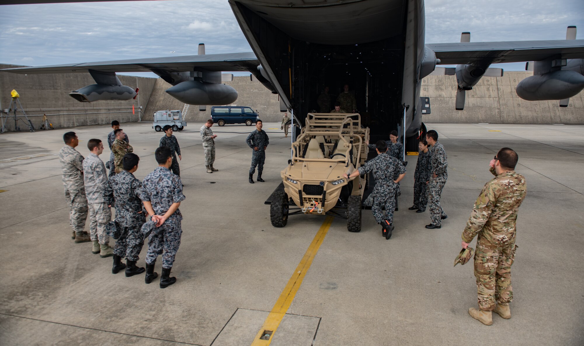 Japan Air Self-Defense Force Airmen and U.S. service members look at a utility terrain vehicle after touring an MC-130H Combat Talon II Nov. 26, 2018, during the 2018 Bilateral Exchange at Kadena Air Base, Japan. The exchange welcomed JASDF Airmen from Okinawa and mainland Japan and enabled them to work and learn with U.S. service members in their work centers. (U.S. Air Force photo by Staff Sgt. Micaiah Anthony)