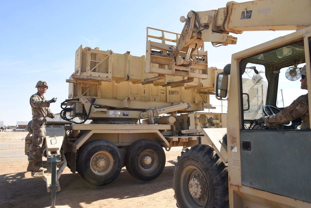 Specialist Tevin Howe, Bravo Battery, 1st Battalion, 43rd Air Defense Artillery Regiment Patriot launcher enhanced operator and maintainer crew member 4 signals for reload, guides Specialist Marcus Gaytan, 1-43 ADA patriot launcher enhanced operator and crew member 2 forklift driver, during training at Al Dhafra Air Base, United Arab Emirates, Jan. 12, 2019.