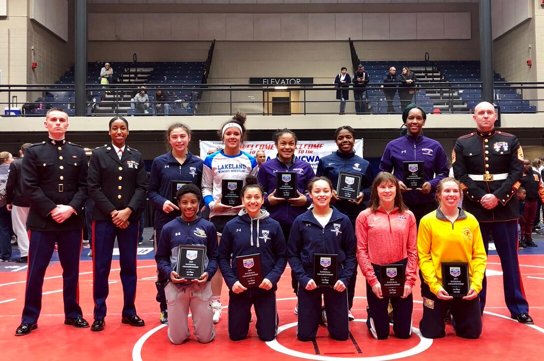(From left to right) 2nd Lt. Ezekiel Johnston, Capt. Alicia Chambers and Gunnery Sgt. Richard Whelan  pose with the national championship wrestlers during the Women’s Collegiate Wrestling Association (WCWA) 2019 National Championship in Marietta, Georgia, February 9, 2019. Wrestlers share the Marines’ fighting spirit, making for a strong partnership with WCWA. WCWA serves as the governing body for women’s college wrestling. (U.S. Marine Corps photo by Capt. Johnny Henderson)