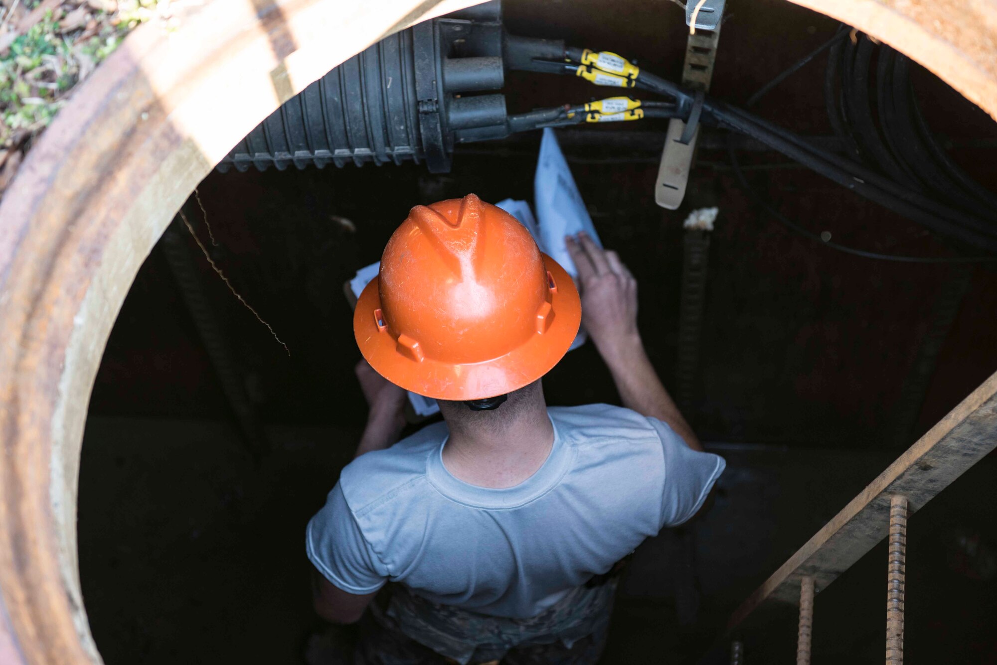 U.S. Air Force Airman 1st Class Jordan Reeve, 633rd Communication Squadron cable and antenna technician, looks over paperwork during routine cable inspections in a manhole on Joint Base Langley-Eustis, Virginia, February 8, 2019.