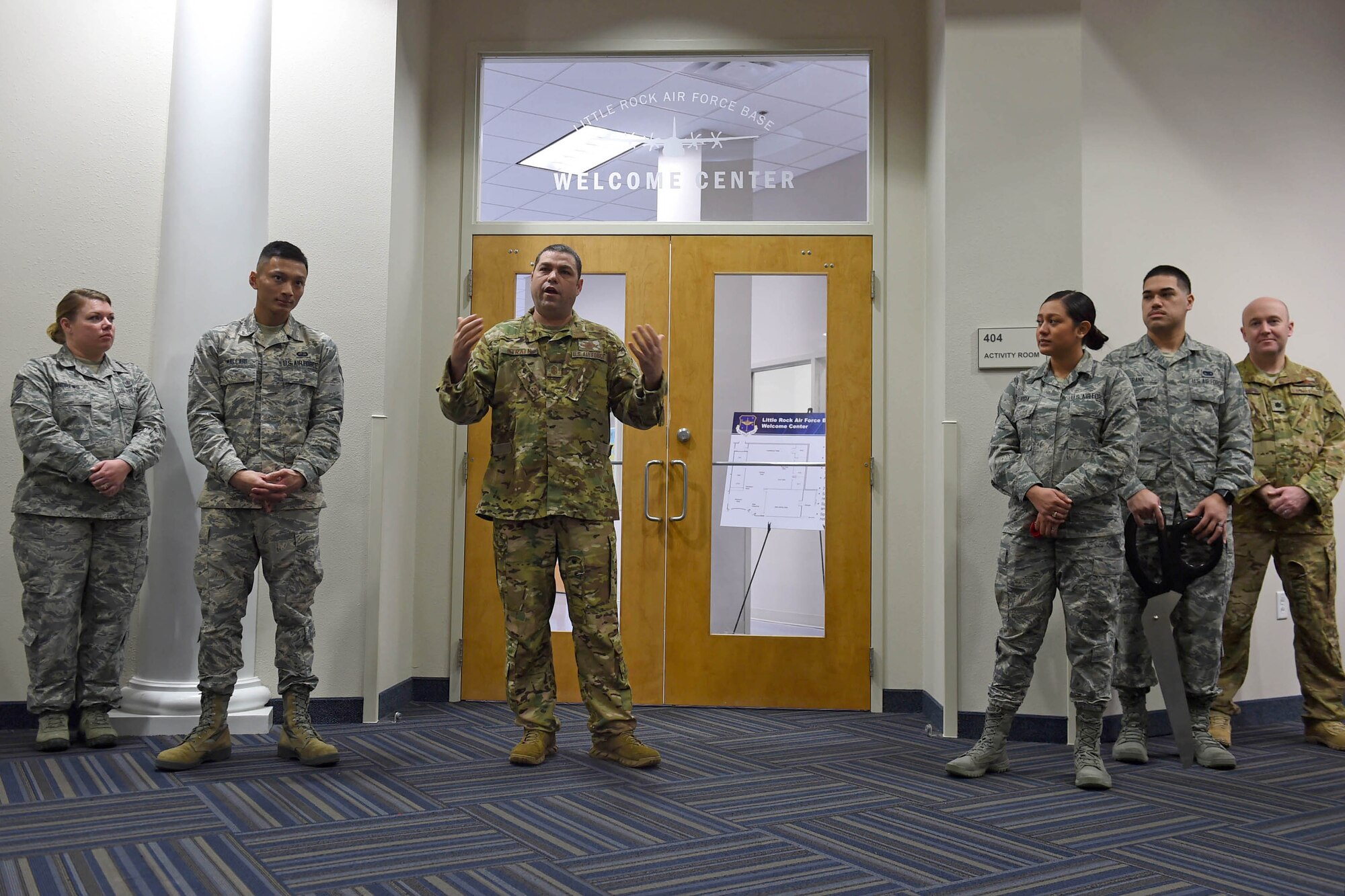 A bunch of Airman stand in front a two doors inside a building