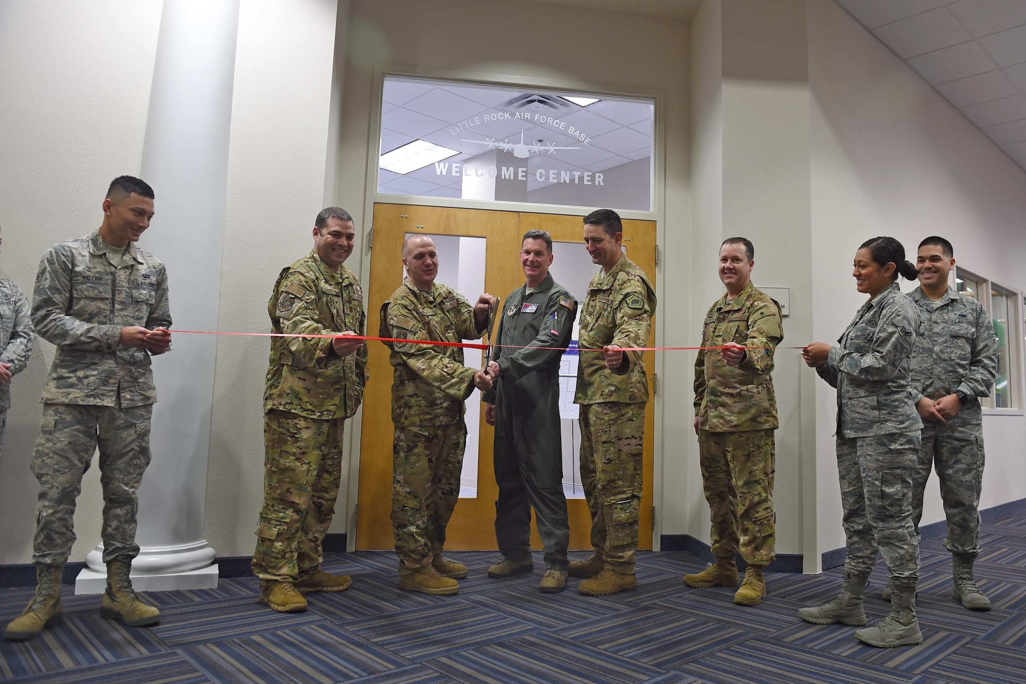 A bunch of Airman stand in front a two doors inside a building