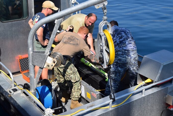 Photo by Lt. Jennifer Jewell 
Navy Experimental Diving Unit 
BU1 Justin Lewis and ND2 Kent Knudson of the Navy Experimental Diving Unit give direction to members of the Montenegrin Navy as part of a recent Humanitarian Mine Action Underwater Explosive Remnants of War Clearance Program collaboration.