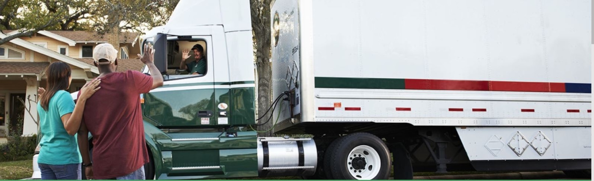A couple waves to a moving truck driver as he arrives.