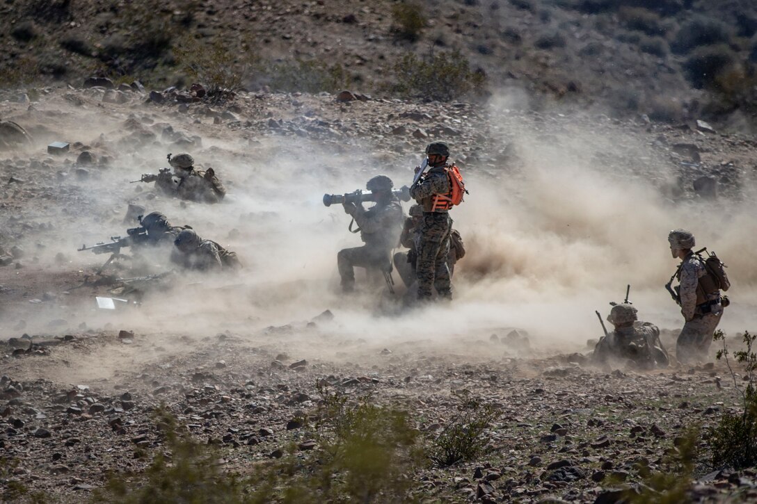 Marines take part in an exercise while dust blows around them.